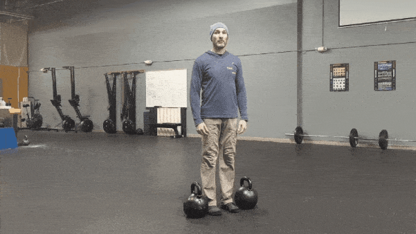 Coach Ryan demonstrates double kettlebell farmer carries.